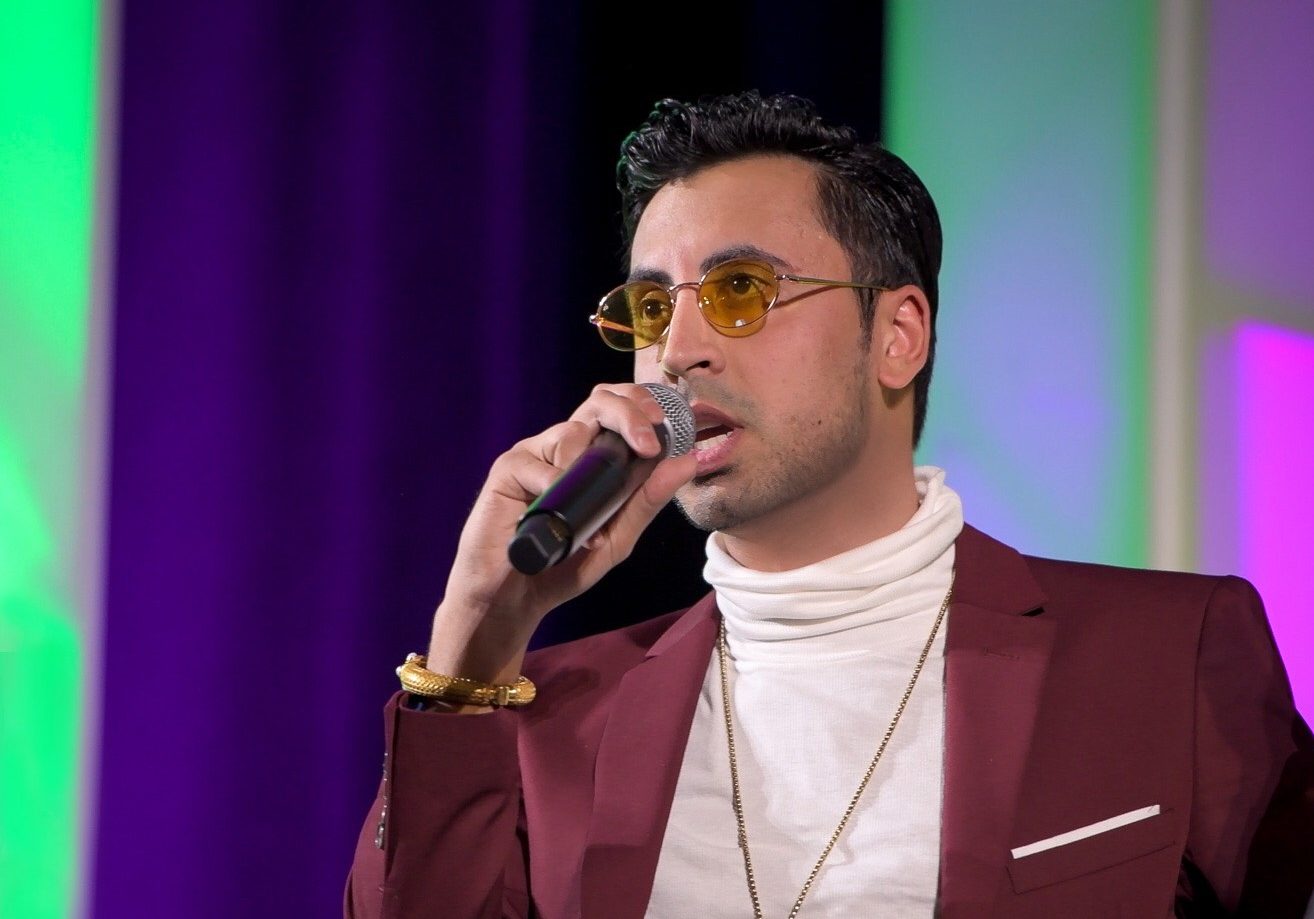 Fam Mirza speaking into a microphone onstage